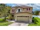Two-story house with tan exterior, red accents, and a two-car garage at 10617 Bamboo Rod Cir, Riverview, FL 33569