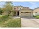 Two-story house with tan exterior, red accents, and a two-car garage at 10617 Bamboo Rod Cir, Riverview, FL 33569