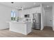 Modern white kitchen with island, stainless steel appliances, and hardwood floors at 10071 Kingsville Dr, Port Charlotte, FL 33981