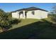 View of the home's rear exterior featuring a covered patio and well-maintained lawn at 10071 Kingsville Dr, Port Charlotte, FL 33981