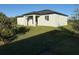 View of the home's rear exterior featuring a covered patio and well-maintained lawn at 10071 Kingsville Dr, Port Charlotte, FL 33981