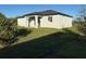 View of the home's rear exterior featuring a covered patio and well-maintained lawn at 10071 Kingsville Dr, Port Charlotte, FL 33981