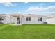 Backyard view of the house with a well-maintained lawn and sliding glass door at 37501 Williamette Way, Zephyrhills, FL 33540