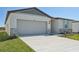 New single-story house with gray siding, stone accents, and a two-car garage at 7806 Gilchrist Springs Dr, Parrish, FL 34219