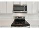 Close up of stainless steel stove top and microwave with white cabinetry at 7818 Gilchrist Springs Dr, Parrish, FL 34219