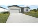 New construction home exterior with gray siding, stone accents, and a long driveway at 31703 Wild Grape Ln, Brooksville, FL 34602