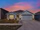 House exterior at dusk, featuring a two-car garage and landscaping at 7729 Rosewood Garden Loop, Tampa, FL 33637