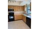 Kitchen features wood cabinets, black appliances, and tile floors at 2513 Lancaster Dr, Sun City Center, FL 33573