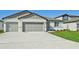 Two-car garage, light-grey exterior, and nicely landscaped front yard at 13851 Richland Gulf Cir, Parrish, FL 34219