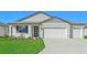 Two-car garage, gray siding, and landscaping at 13855 Richland Gulf Cir, Parrish, FL 34219