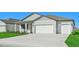 Two-car garage, gray siding, and landscaping at 13855 Richland Gulf Cir, Parrish, FL 34219