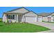 Two-car garage, gray siding, and landscaping at 13855 Richland Gulf Cir, Parrish, FL 34219