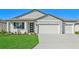 Two-car garage, gray siding, and landscaping at 13855 Richland Gulf Cir, Parrish, FL 34219