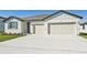Two-car garage, light-colored house with gray accents, and a concrete driveway at 13859 Richland Gulf Cir, Parrish, FL 34219