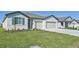 Light-colored house with gray accents, two-car garage, and a grassy lawn at 13859 Richland Gulf Cir, Parrish, FL 34219