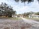 Front view of a single story home with a driveway and mature trees at 4935 Mockingbird Dr, Dade City, FL 33523