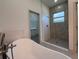 Bright bathroom features a stand alone tub, walk in shower with window, and stone tile at 135 Sunset Rd, Rotonda West, FL 33947