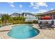 Relaxing kidney-shaped pool with patio furniture and red umbrella at 505 Sally Lee Dr, Ellenton, FL 34222