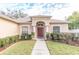 House exterior featuring a red front door, arched entryway, and neatly landscaped yard at 12908 Cattail Shore Ln, Riverview, FL 33579