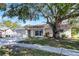 Tan house with brown roof, attached garage, and a large tree in the front yard at 7939 Riverdale Dr, New Port Richey, FL 34653