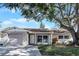 Tan house with brown roof, attached garage, and a large tree in the front yard at 7939 Riverdale Dr, New Port Richey, FL 34653