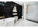Luxurious bathroom featuring sleek black and white marble tile, a modern gold shower system, and a freestanding tub at 1390 Eastfield Dr, Clearwater, FL 33764
