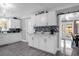 Contemporary kitchen boasts white cabinets, mosaic backsplash, modern appliances, and views to dining and living areas at 1390 Eastfield Dr, Clearwater, FL 33764