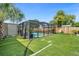 Backyard pool features a screened enclosure with a grass surround, ideal for relaxing and outdoor entertainment at 1390 Eastfield Dr, Clearwater, FL 33764