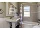 Bathroom with pedestal sink, shower/tub combo and window at 7108 N 10Th St, Tampa, FL 33604