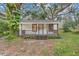 Quaint white cottage with a wooden porch and tree-lined yard at 7495 Mitchell Rd, Brooksville, FL 34601