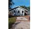 Gray bungalow with brick paver driveway, landscaped yard, and partial water view at 718 New York St, Clearwater, FL 33756