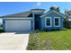 Newly constructed light blue house with a two-car garage and manicured lawn at 7340 Bass St, Englewood, FL 34224