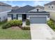 Single-story house with gray exterior, landscaping and two car garage at 9474 Sanders Park Pl, Seffner, FL 33584