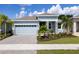 Curb appeal abounds in this charming house featuring a light blue exterior, gray stone accents and lush landscaping at 1017 Signet Dr, Apollo Beach, FL 33572