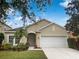 Tan house with white garage door, landscaping, and palm tree at 706 Fern Leaf Dr, Ruskin, FL 33570