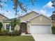 Tan house with white garage door, landscaping, and palm tree at 706 Fern Leaf Dr, Ruskin, FL 33570