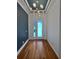 Bright entryway with hardwood floors, a modern chandelier, and a blue accent wall at 8955 Garden Party Dr, Land O Lakes, FL 34637