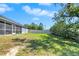 Spacious backyard with grassy area and screened porch view at 13474 Tune Ln, Spring Hill, FL 34609