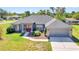 Brick house with gray garage door and red front door, nicely landscaped lawn at 13474 Tune Ln, Spring Hill, FL 34609