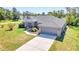 Single-story home with gray roof, red front door, and a large yard at 13474 Tune Ln, Spring Hill, FL 34609