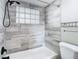 Modern bathroom with gray tile, shower/tub combo, and a glass block window at 6941 Twilite Dr, Port Richey, FL 34668