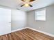 Well-lit bedroom with wood-look floors, ceiling fan and an adjacent bathroom at 6941 Twilite Dr, Port Richey, FL 34668