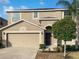 Two-story house with a tan exterior, two-car garage, and manicured lawn at 16617 Magnolia Reserve Pl, Wimauma, FL 33598