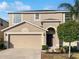 Two-story house with a tan exterior, two-car garage, and manicured lawn at 16617 Magnolia Reserve Pl, Wimauma, FL 33598