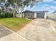 Updated home exterior boasts a gray and white color scheme, landscaping, and a spacious driveway at 1414 Wickham Ln, Holiday, FL 34691