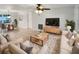 Bright and airy living room features neutral decor, comfy seating, and a large TV at 1414 Wickham Ln, Holiday, FL 34691