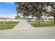 One-story home with a white exterior, attached garage, and tree-lined street at 4406 Woodtrail Blvd, New Port Richey, FL 34653
