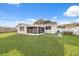 Back exterior view showing a screened patio and lawn at 4406 Woodtrail Blvd, New Port Richey, FL 34653