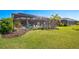 A screened-in in-ground pool with lounge chairs surrounded by lush green grass and palm trees in the backyard at 4606 Pond Brook Ct, Bradenton, FL 34211