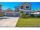 Beautiful two-story gray home with a three-car garage, stone accents, a well manicured lawn, and lush landscaping at 4606 Pond Brook Ct, Bradenton, FL 34211